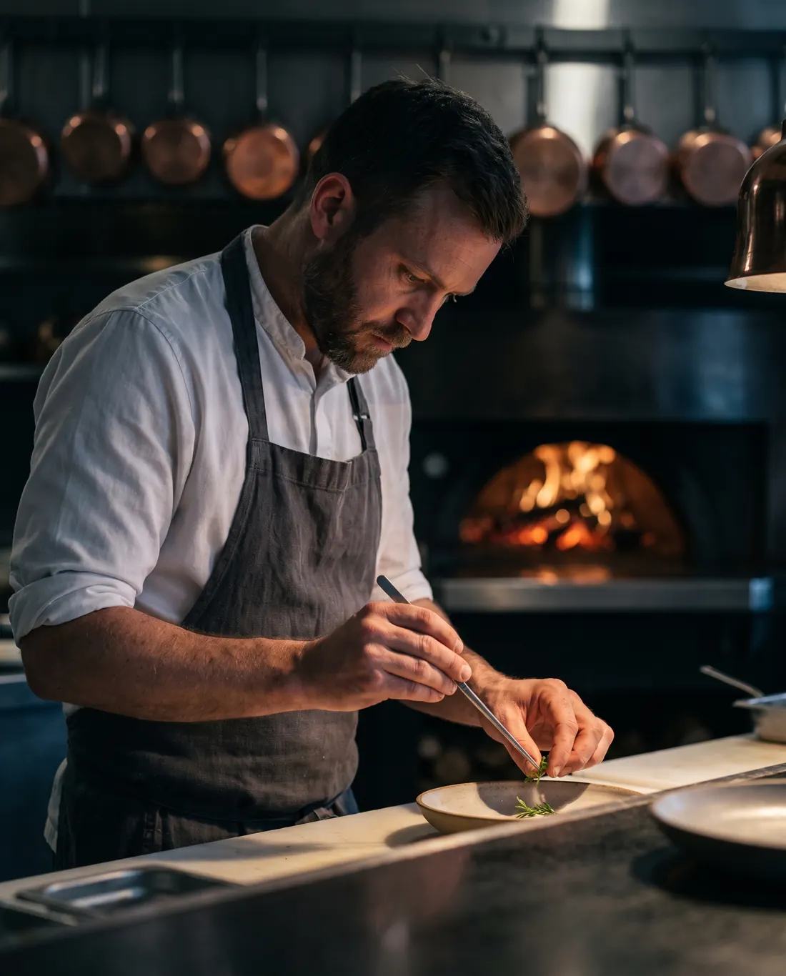 Chef Daniel Ashworth plating a dish at the pass with tweezers